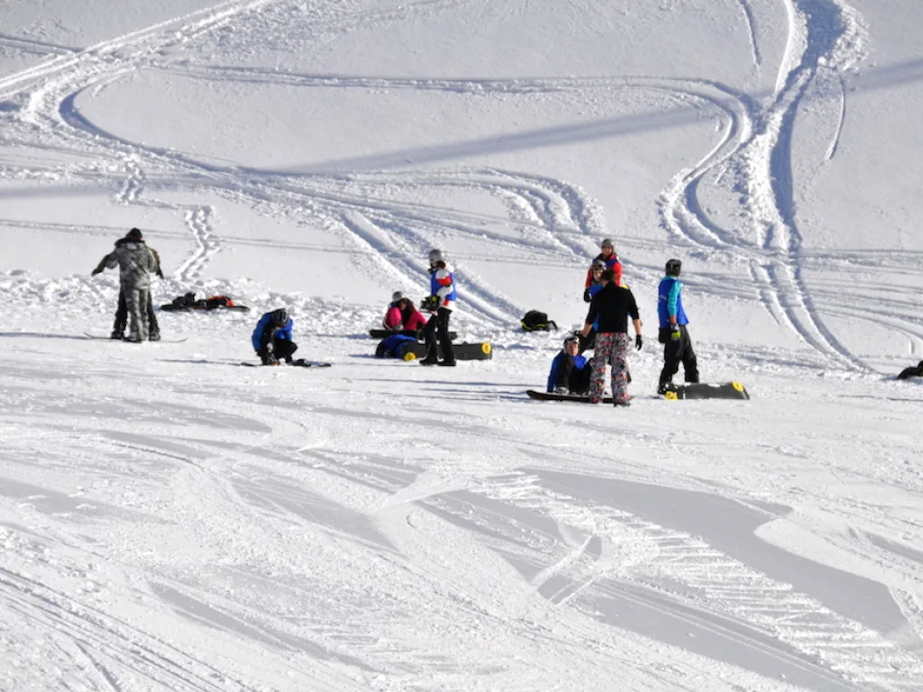 Jugendliche sitzen und liegen im Schnee neben ihren Spuren.